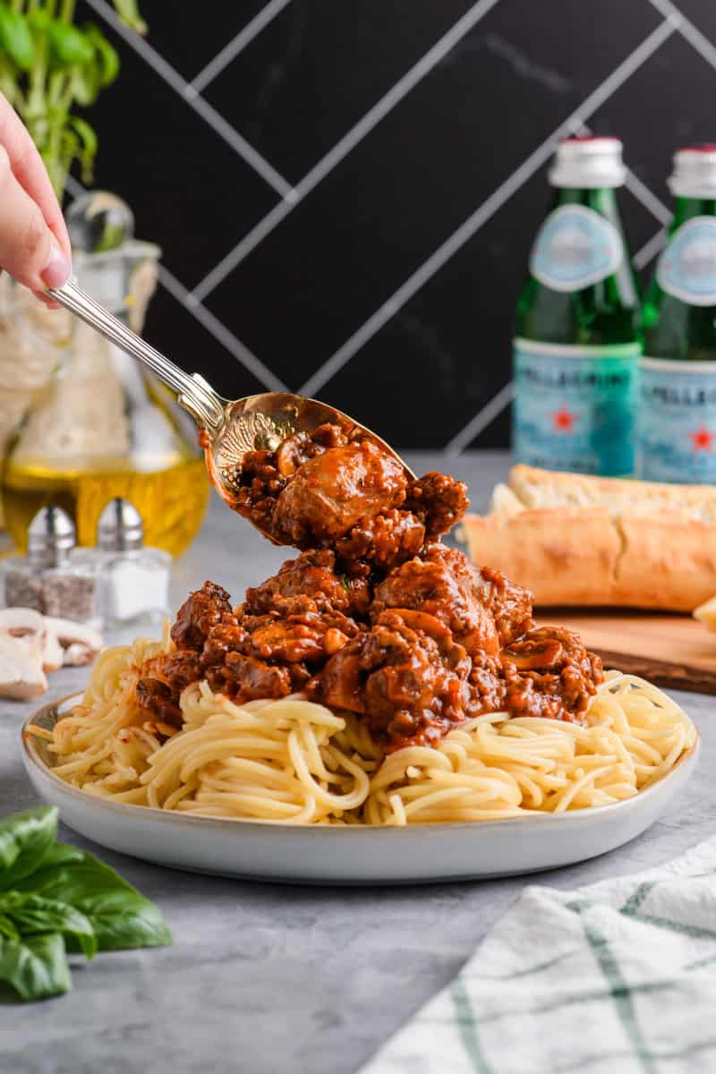 Sauce from Italian Sausage Spaghetti being spooned on top of pasta.