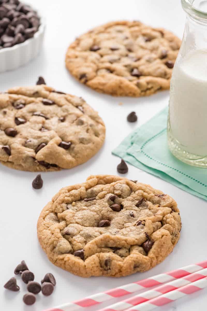 Angled shot of three Best Big Fat Chewy Chocolate Chip Cookies on marble surface.