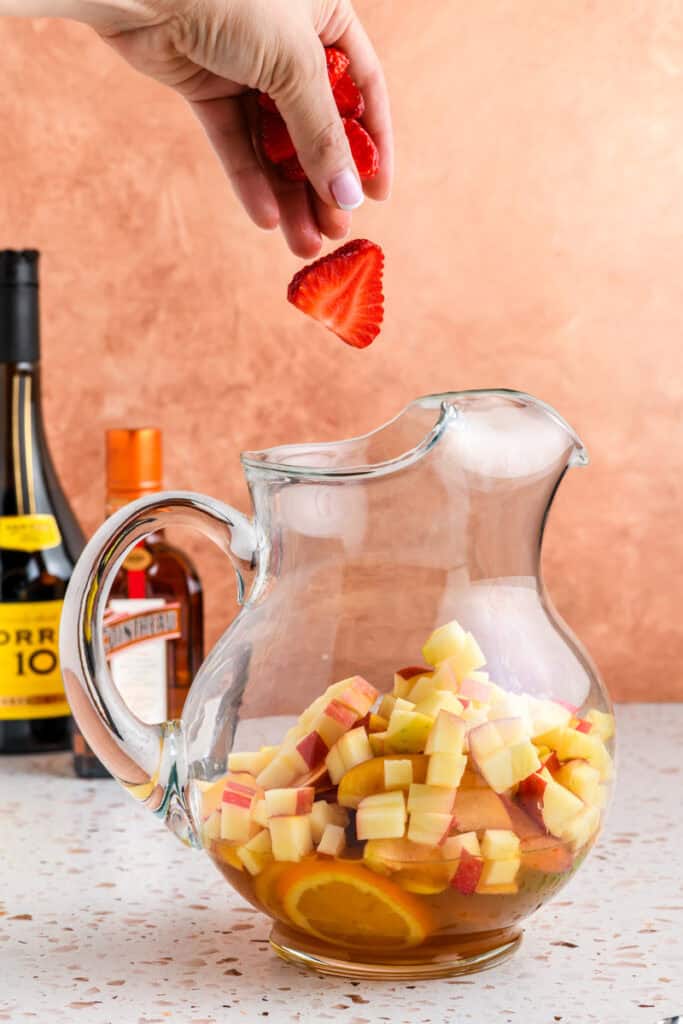 Strawberries going into the pitcher for Sparkling Sangria.