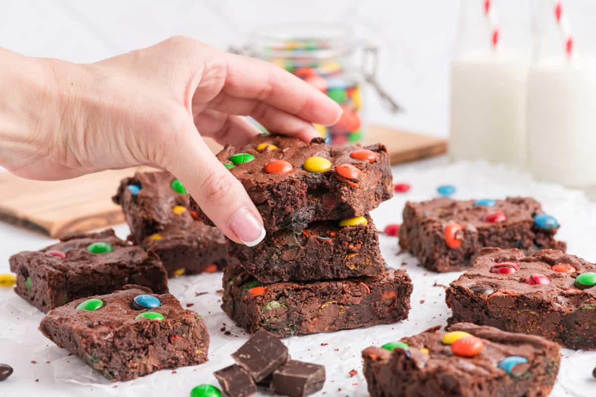 Hand taking a M&M Brownie from stack.