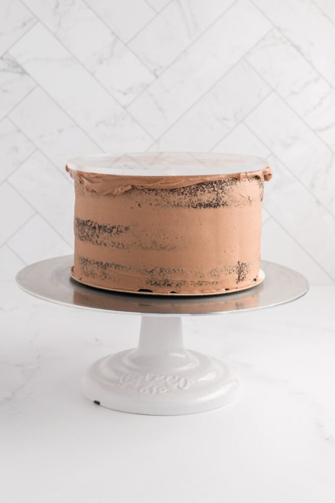 M&M Chocolate cake with crumb coat and acrylic disc on top.