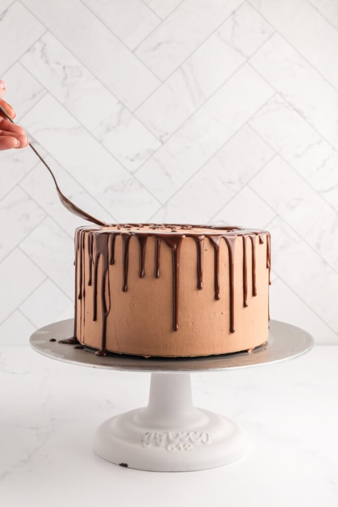 Chocolate ganache being applied to frosted M&M Chocolate Cake.
