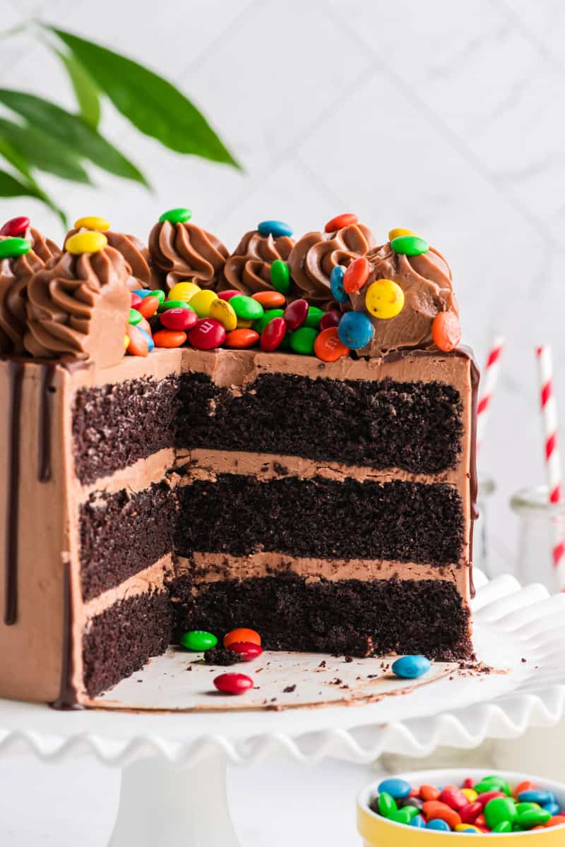 Close up shot of sliced M&M Chocolate Cake on white cake stand.