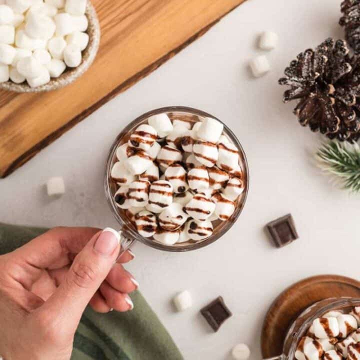 Overhead shot with hand grabbing a cup of Slow Cooker Hot Chocolate.