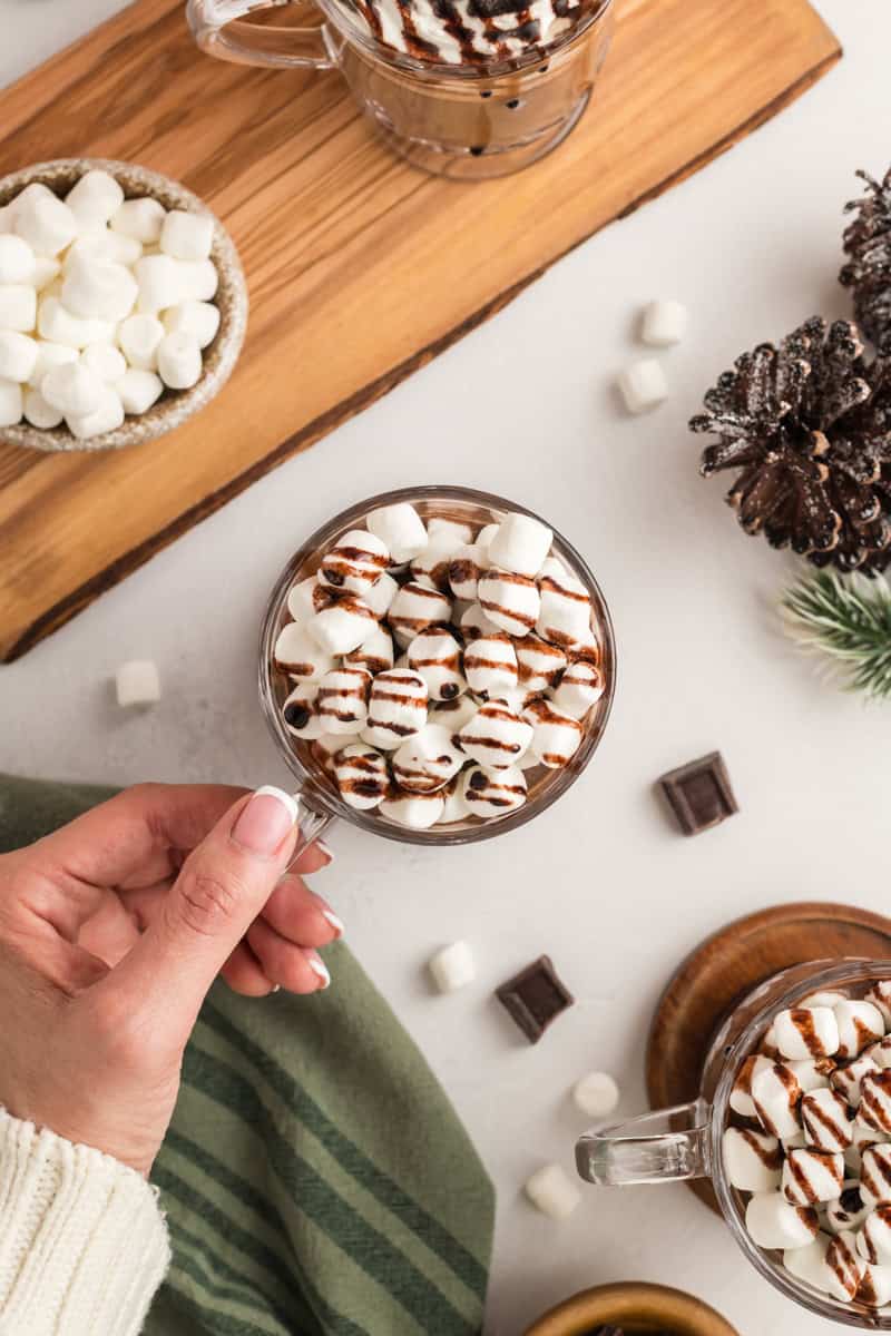 Overhead shot with hand grabbing a cup of Slow Cooker Hot Chocolate.